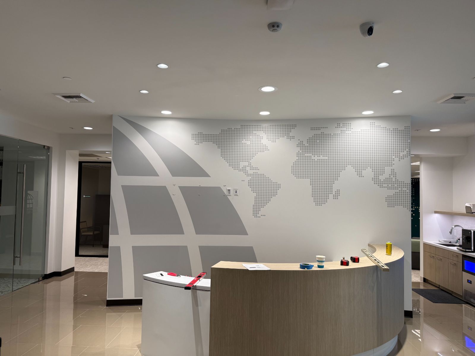 Curved reception wall with a dotted world map and globe grid lines applied in printed and cut vinyl