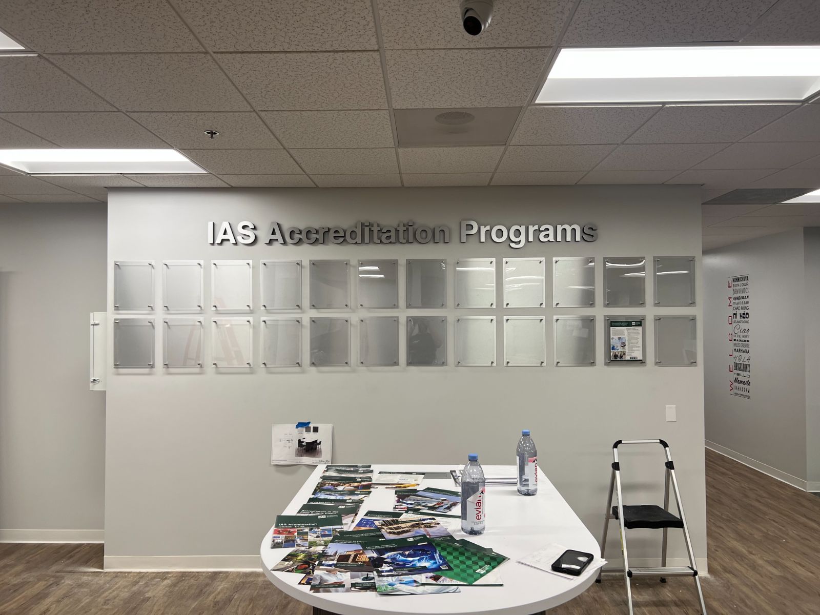 IAS Accreditation Programs corporate feature wall: brushed aluminum dimensional letters above a grid of acrylic document display frames